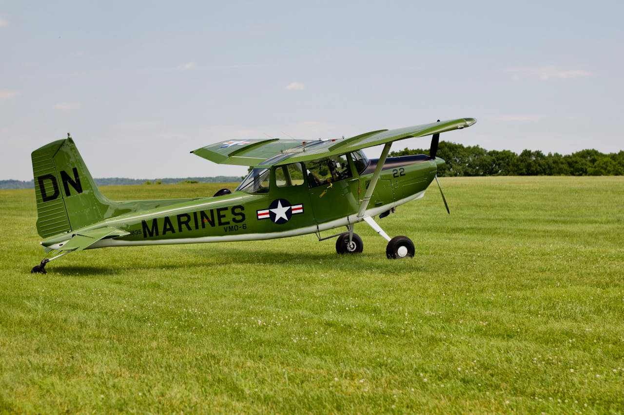 A classic military aircraft stationed on an open green field under a clear sky.