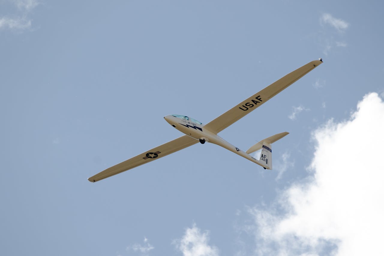 A USAF glider flying high at the Air Force Academy, Colorado against a clear sky.