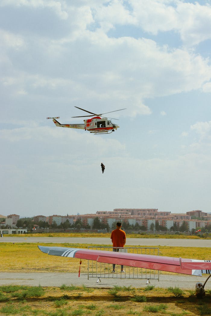 gallery-6 A helicopter performs training exercises over an airfield while a man observes from the ground.