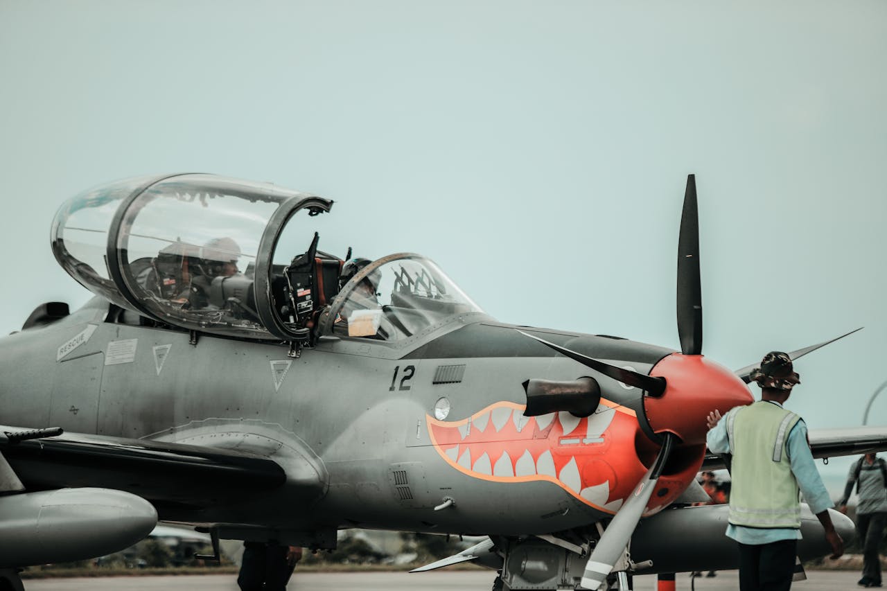 hero-img-01 A detailed view of a military aircraft featuring shark teeth design on the runway with crew personnel.