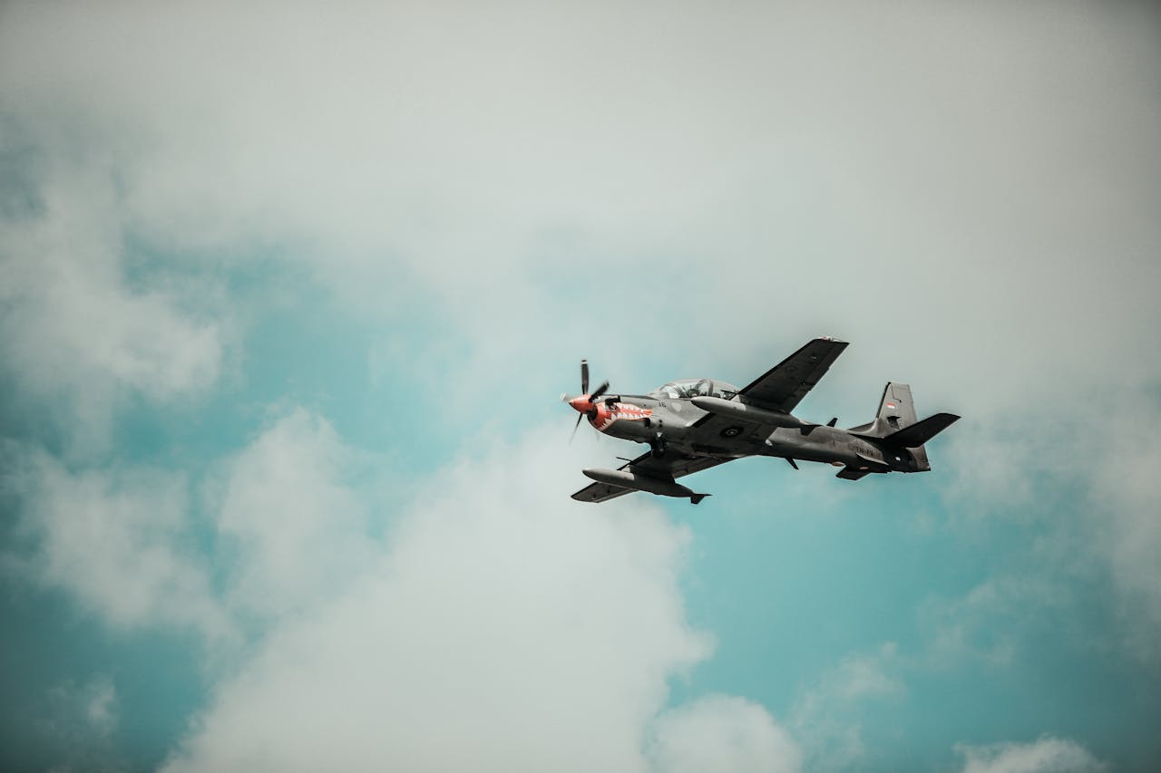 A military aircraft flying through a bright cloudy sky, showcasing aviation power.