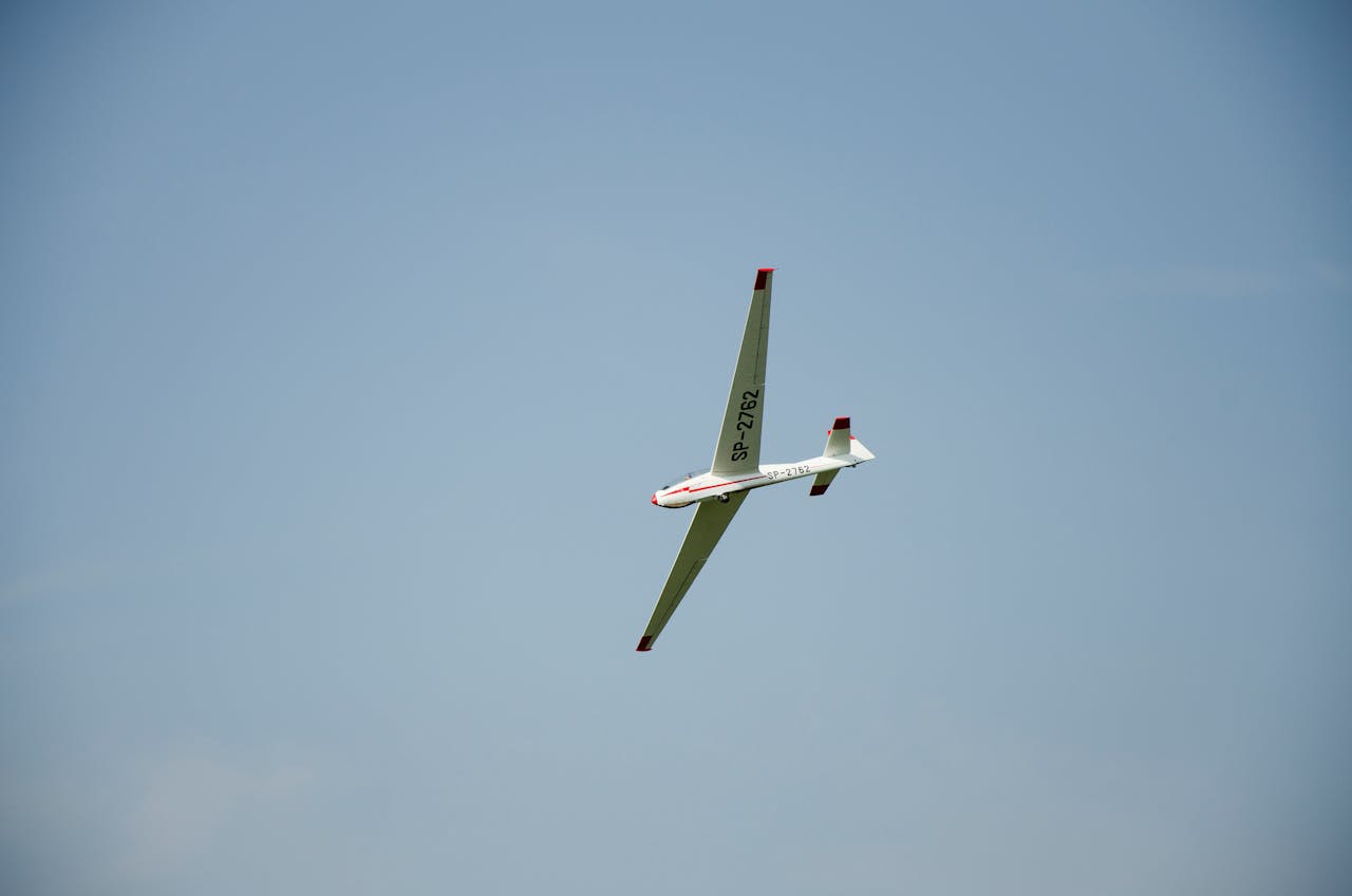 gallery-4 A sleek white glider aircraft gracefully flying against a clear blue sky.