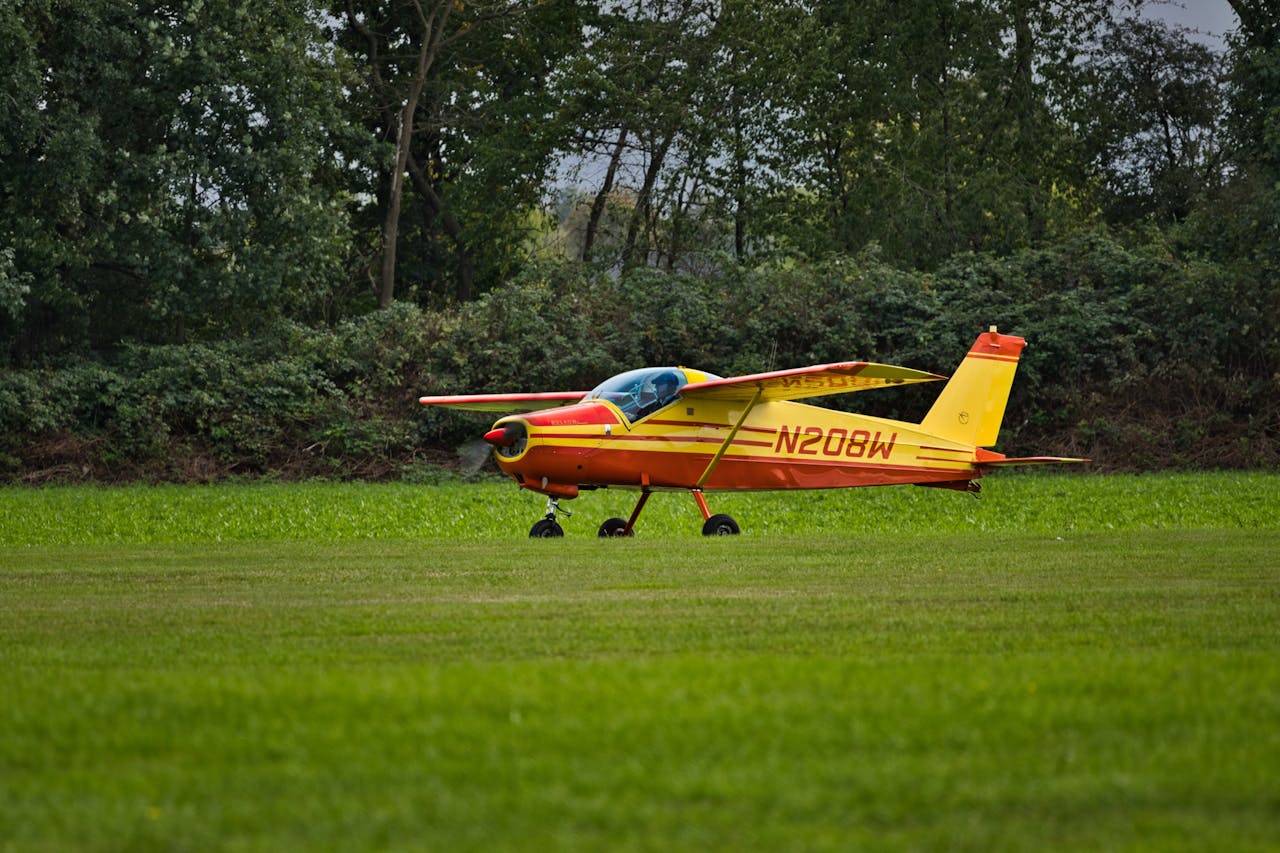 our-services-2 A bright yellow and red light aircraft parked on a lush green grass airstrip.