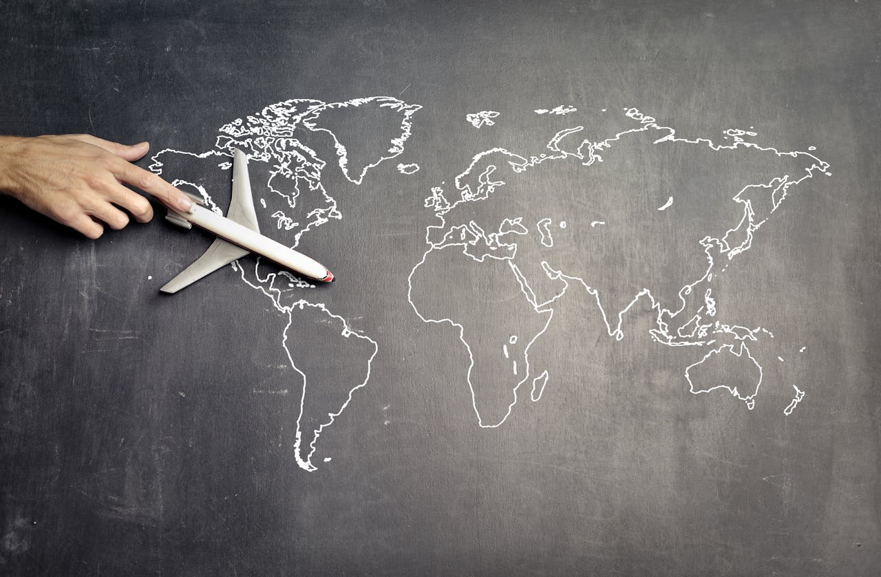 why-choose-us From above of crop anonymous person driving toy airplane on empty world map drawn on blackboard representing travel concept