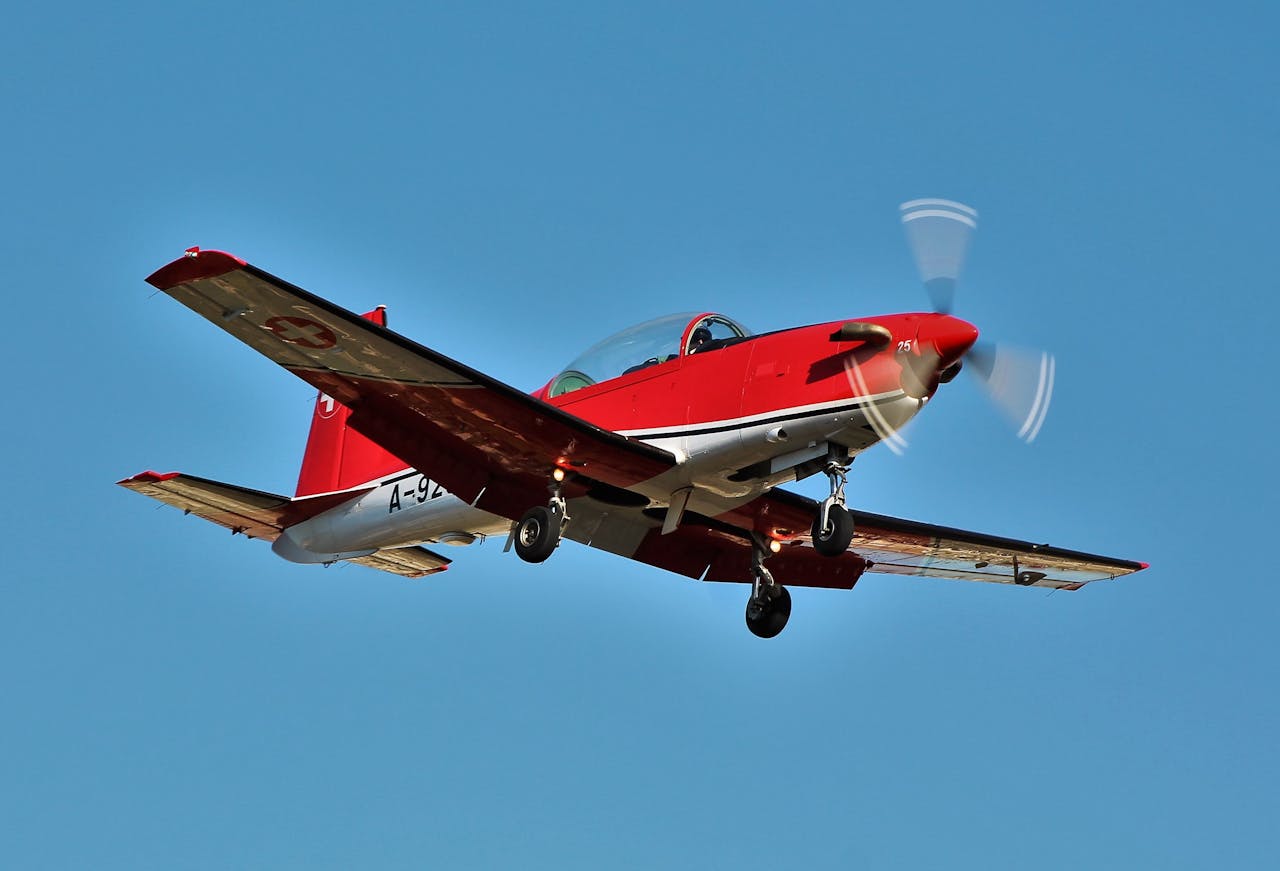 Dynamic shot of a red turboprop plane flying against a clear blue sky.