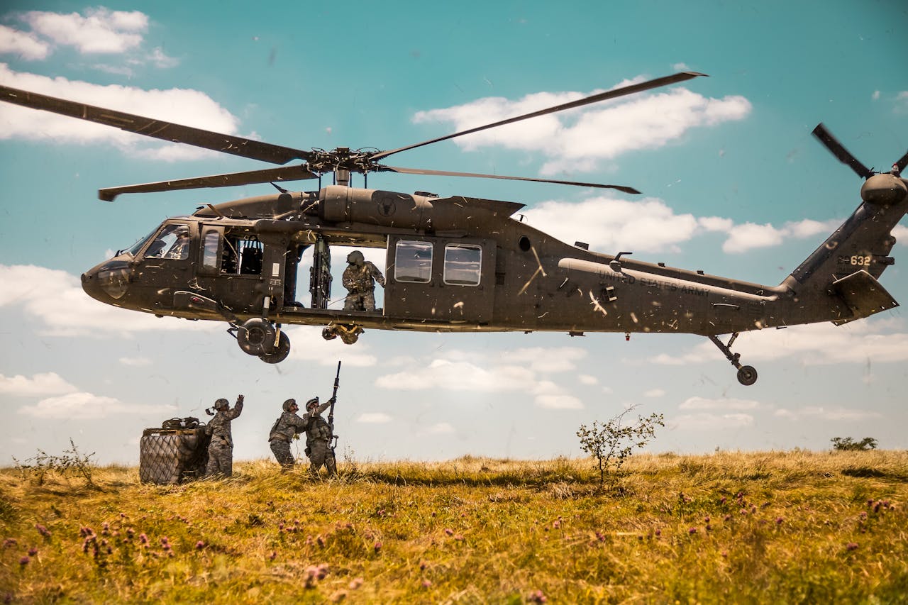 our-services-3 A Blackhawk helicopter in a military training mission with soldiers on a field.